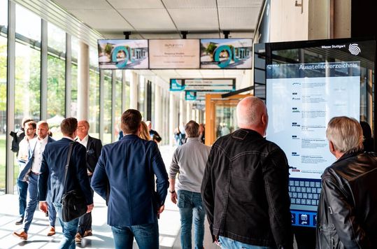 Visitors on the grounds of Messe Stuttgart use a large touchscreen information kiosk to call up the Online Exhibitor Directory (OED) for AMB.(Source:  Messe Stuttgart)
