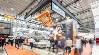 Auf der Stuttgarter Logimat lieferte ein AMR mit Moveli-Aufsatz eine Palette mit Kartons dem Trapo Cobot Palletizer an, der ohne Zaun palettieren und depalettieren kann. Den Gästen reichte der Cobot einen XXL-Thermobecher als Gruß. (Bild: Trapo)