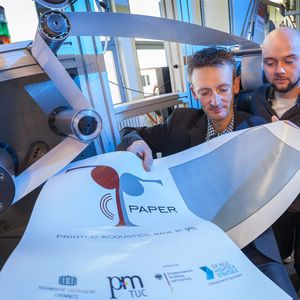 Dr. Georg Schmidt (l.) und Student Robert Eland kontrollieren an einer Rolle-zu-Rolle-Druckmaschine im Labor der Professur Printmedientechnik die Qualität eines Probedruckes.