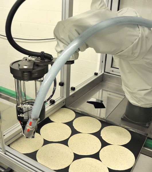 Roboter beim Dressieren von Tortenböden. Wie alle Konditoren in der Backstube trägt auch er einen weißen Schutzanzug. Nur die Haube bleibt ihm erspart. (Bild: Foitzik)