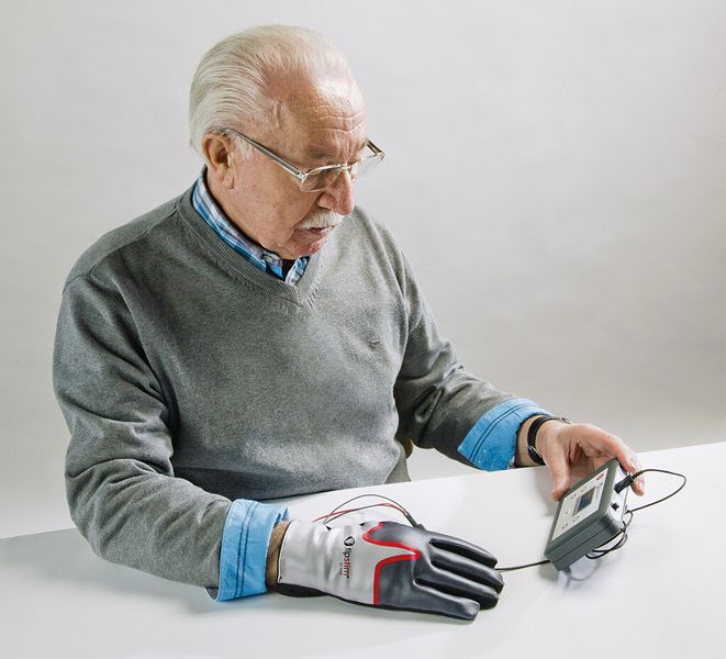 Tipstim, ein Sensorhandschuh mit einem Steuergerät als Impulsgeber: Durch sensible Stimulation der Fingerspitzen werden in den für die Hand zuständigen, zugeordneten Gehirnarealen plastische Prozesse ausgelöst.  (Bosana Medizintechnik)