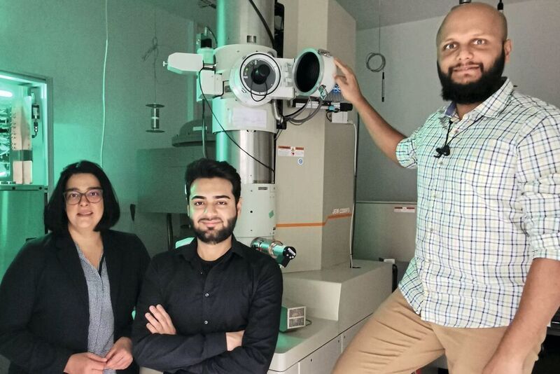 Nutzen ausgeklügelte mikroskopische Methoden, um die Grundlage für bessere Batterien zu schaffen (von links): Professorin Dr. Kerstin Volz, Shamail Ahmed und Dr. Anuj Pokle vor dem Raster-Transmissionselektronenmikroskop. (Thomas Demuth)