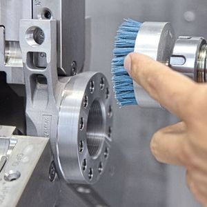 Seit Ende 2024 wird in der Produktion der Herzog Systems AG auf Bürsttechnologie gesetzt, um Komponenten auf CNC-Bearbeitungszentren zu entgraten. Damit konnte auf einem flexiblen Fertigungssystem eine voll autonome Fertigung inklusive 3D-Vermessung realisiert werden. Im Bild eine Zeintra-Schafttopfbürste mit auf das Bauteil und den Werkstoff abgestimmten Filament (blau). (Bild:  Matthias Böhm)