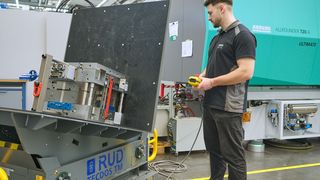 Ein Arburg-Mitarbeiter handhabt ein tonnenschweres Spritzgießwerkzeug auf dem RUD Tecdos TM ergonomisch und sicher. (Bild: RUD / Jensen)