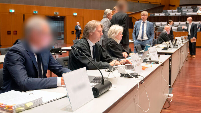Einer der vier Angeklagten (links) sitzt zu Prozessbeginn in der Stadthalle Braunschweig. 