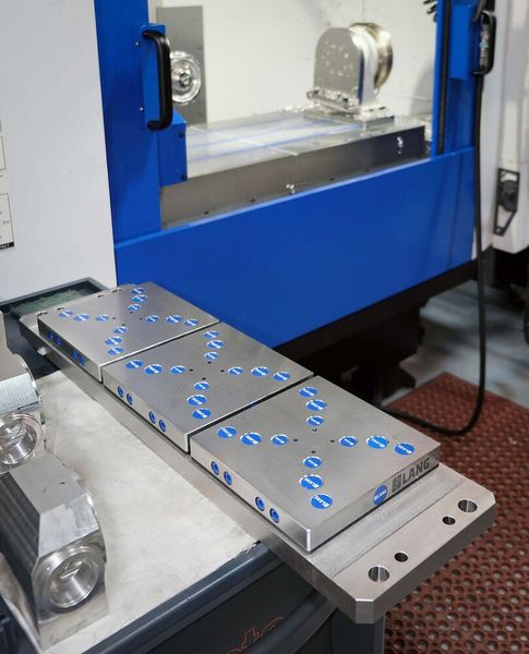 In the foreground is the trunnion equipped with Lang workholding plates that is usually rotated by the 4th-axis indexing head on the Brother Speedio’s table. (Source: Whitehouse Machine Tools )