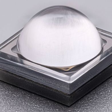 Fern-UVC-LED mit Linse und Reflektor: Nahaufnahme einer quadratischen LED mit transparenter, kuppelförmiger Linse auf dunkler Grundplatte. Das hermetisch geschlossene Gehäuse sorgt für höhere Zuverlässigkeit und Robustheit unter anspruchsvollen Umgebungsbedingungen. (Bild: FBH_Schurian)