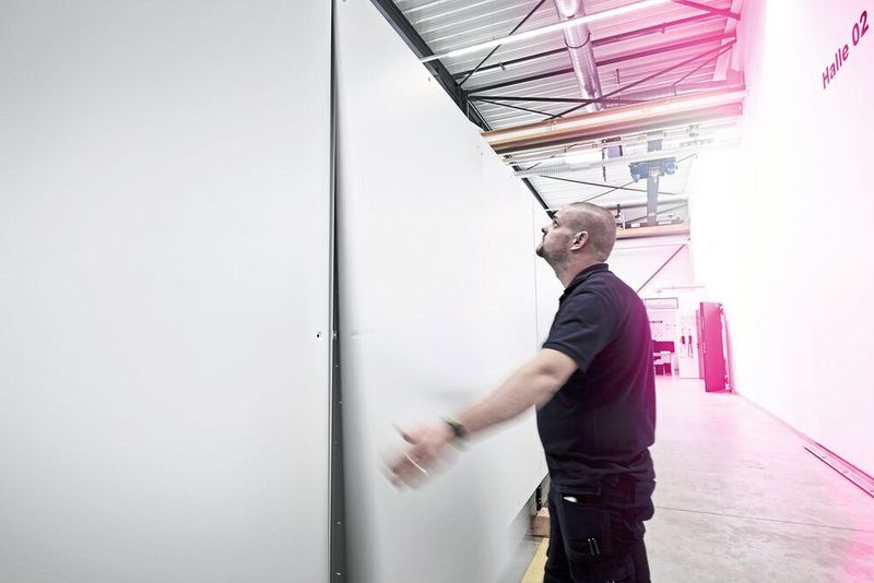 Bild 4: Eugen Franzen von der Controller Steuerungstechnik demonstriert die Einhandmontage. Die Rückwand ist einfach von oben einzuhängen und bleibt sicher in der Position, bis die Schrauben angezogen sind. (Rittal)