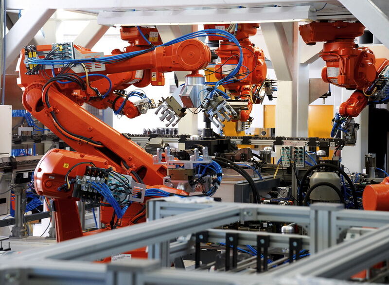 Trois robots à bras articulé déposent les composants sur des plateaux porte-pièces. (Image: Bosch Rexroth)