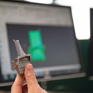 Die erste generativ gefertigte Turbinenschaufel «SGT400 Stage 1» (im Hintergrund die NX-Software) wurde von Materials Solutions, einem Siemens-­Service-Provider für die additive Fertigung, produziert.