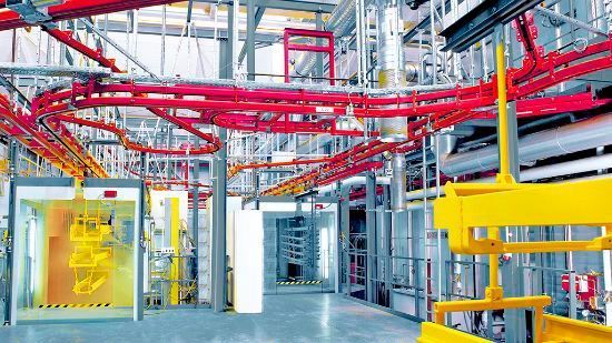 Die Elektrohängebahn führt die Werkstücke der Lackierkabine (links) zu. (Eisenmann)
