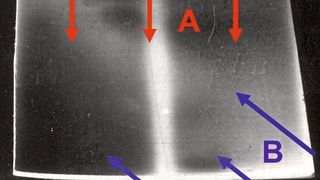 Decoloración irregular del PVC gris claro al ser irradiado con una lámpara de xenón (A, flechas rojas). Esto se debe a pequeñas diferencias en la temperatura superficial provocadas por el flujo de aire de refrigeración que entra por los laterales (B, flechas azules). (Fuente:Trubiroha, Kockott, Boxhammer)