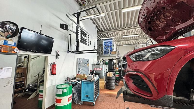 Symbol einer erfolgreichen Werkstatt: Der FAS-Kalibrierstand von 1a Autoservice Amhaz hing in der alten Werkstatt am Kranhaken unter der Decke. Wenn er gebraucht wurde, musste er erst abgelassen, positioniert und nach getaner Arbeit wieder hochgezogen werden – zeitaufwendig, aber mangels Platz die einzige Lösung.(Bild:  Schreiner – VCG)