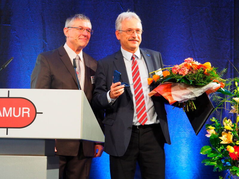 Feierlicher Moment im Rahmen der Eröffnung: Dr. Wilhelm Otten übergibt die goldene Ehrennadel an Dr. Joachim Birk von der BASF. (Sabine Mühlenkamp)