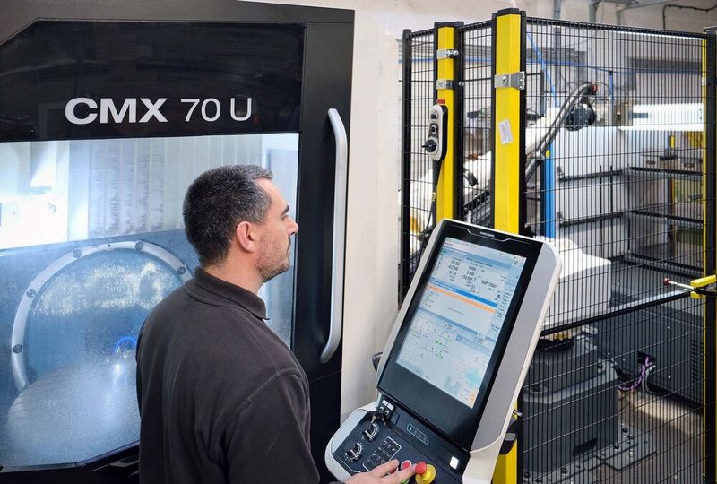 Mr Slimm at the control of the automated DMG Mori CMX 70 U VMC. The robot enclosure with safety fence and light curtain may be seen in the background. (Source: Whitehouse Machine Tools )