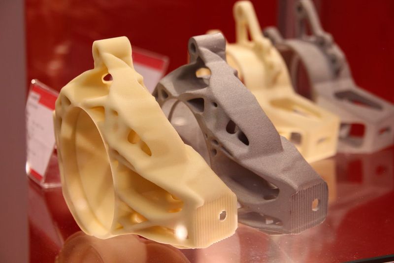 Gelblich ist im Vordergrung zu Demonstrationszwecken die von Altair optimierte Radaufhängung in 3D-gedruckter Ausführung und dahinter die einsatzfähige Variante aus Aluminium-Druckguß. Die Formen sind dabei von Voxeljet-Anlagen erstellt worden. (Bild: Königsreuther)