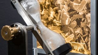 Exponat zu plättchenförmigen Zinkphosphat-Partikeln für verbesserten Korrosionsschutz: Wegen der ungeordneten Verteilung der Plättchen ist ein „Durchrieseln in der Sanduhr“ wie bei kugelförmigen Partikeln  nicht möglich.  (Ollmann)