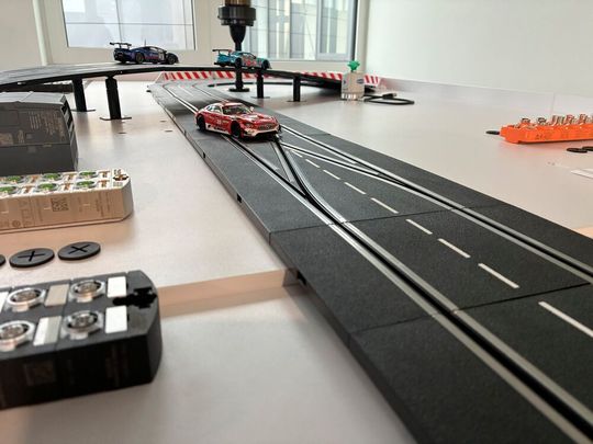 Eine Miniaturautorennbahn zeigt live, wie IO-Link Geräte Renndaten erfassen und visualisieren – Praxisautomatisierung im Kleinformat.(Bild:  Profibus Nutzerorganisation)