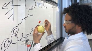 Dawit T. Filmon, Mitarbeiter von Prof. Nicolas Plumere, hält einen Ausgangsstoff für die Seitenketten des schützenden Polymers in seinen Händen.
 (Jan Winter / TUM)