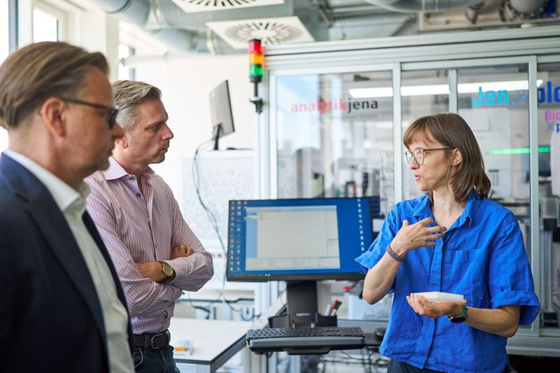 Zusammenspiel von Forschung und Mittelstand: Nachwuchsgruppenleiterin Luzia Gyr und Lars Böttcher von Analytik Jena erläutern Sascha van Beek (mitte links) die Zusammenarbeit rund um die Robotik-Plattform Jen-Xplore. (Bild: Anna Schroll/Leibniz-HKI)