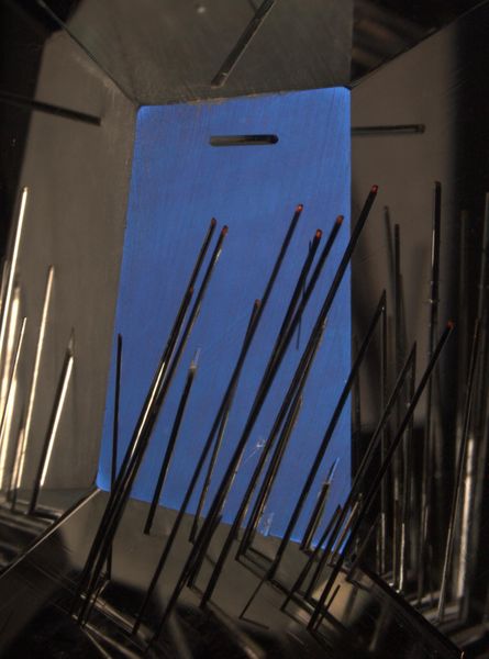 Einschlüsse von Rutilnadeln in Quarz, Minas Gerais, Brasilien. Dass Einschlüsse in Edelsteinen keine Fehler, sondern natürliche Merkmale sind, die auch zur Gestaltung eines Schmucksteins verwendet werden können, beweist der abgebildete Stein des berühmten Schliff-Designers Bernd Munsteiner. Bildhöhe: ungefähr 16 mm, Kombination von Durchlicht und seitlichem Auflicht (Glasfaser), gekreuzte Polarisatoren, Rot 1-Kompensator, Leica MZ16 Stereomikroskop (Michael Hügi, Schweizerisches Gemmologisches Institut)