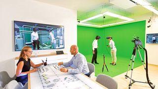 Abb.1: Virtuelle Realität im Autodesk VR Lab München: Die Personen in der Greenbox „begehen“ das BIM-Modell mittels VR-Brille und begutachten so u.a. Wege und Flächen. Gleichzeitig werden die beiden von außen beraten und geleitet. So können Fachplaner, Nutzer und Sachverständige (hier für Laborabnahme) das Gebäude bereits in der Planung bewerten und optimieren, was die kostenintensive Änderungen in späteren Phasen stark reduziert. (TÜV Süd)