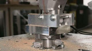 Der 6-Komponenten Kraft-/Momenten-Sensor von Kistler misst exakt die dynamischen Kräfte und Momente, die auf die Stichsäge einwirken. Die Säge ist kopfüber montiert. (Kistler Gruppe)