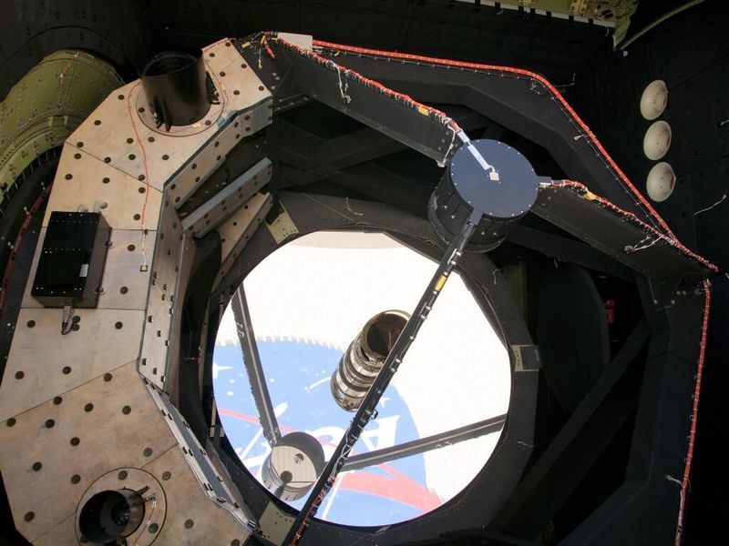 Das NASA-Logo auf dem Gebäude 703 der Dryden Aircraft Operation Facility spiegelt sich im Hauptspiegel des SOFIA-Teleskops (NASA)