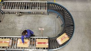 Aus der Vogelperspektive: Eine Mitarbeiterin in einem Lagerhaus scannt Kartons auf einem Förderband. (Bild: Oracle)