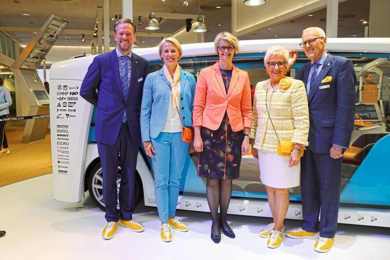 Margrit Harting möchte, dass alle Mitarbeiter bei langen Messetagen wenigstens bequeme Schuhe tragen. Die gelben Sneakers sind zudem zu einem Markenzeichen geworden. Im Bild (v.l.): Philip Harting, Maresa Harting-Hertz, Bundesministerin für Bildung und Forschung Anja Karliczek, Margrit und Dietmar Harting auf dem Messestand der Hannover Messe 2018. (Harting)
