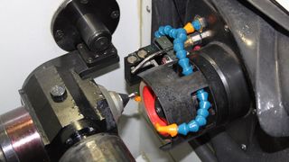 Arbeitsbereich des CNC-Bohrer-Schleifzentrums NC18 mit der in drei Achsen verfahrenden Schleifspindeleinheit und der Vertikal-/Horizontal-Schwenkeinheit mit Bohreraufnahme. (Bild: Haller Werkzeugschleiftechnik)