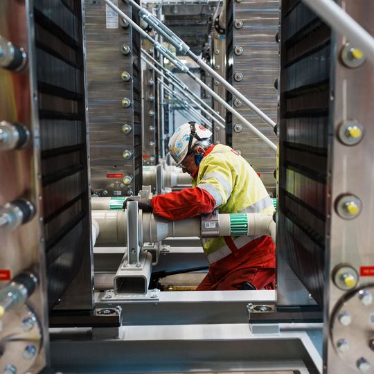 Die letzten Zentimeter sind Handarbeit: Monteure verbinden die einzelnen Elektrolyseur-Module miteinander. Bei Fertigstellung werden insgesamt 72 „Stacks“ eine Kapazität von 54 Megawatt haben.(Bild:  BASF)