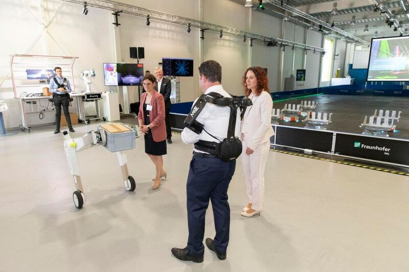 ¡La política se encuentra con la IA! El Ministro Federal de Trabajo Hubertus Heil (entre las damas) probó un exoesqueleto durante su visita al Fraunhofer-IML de Dortmund y también conoció al robot móvil autónomo "evoBOT". Lea aquí los antecedentes de la visita.