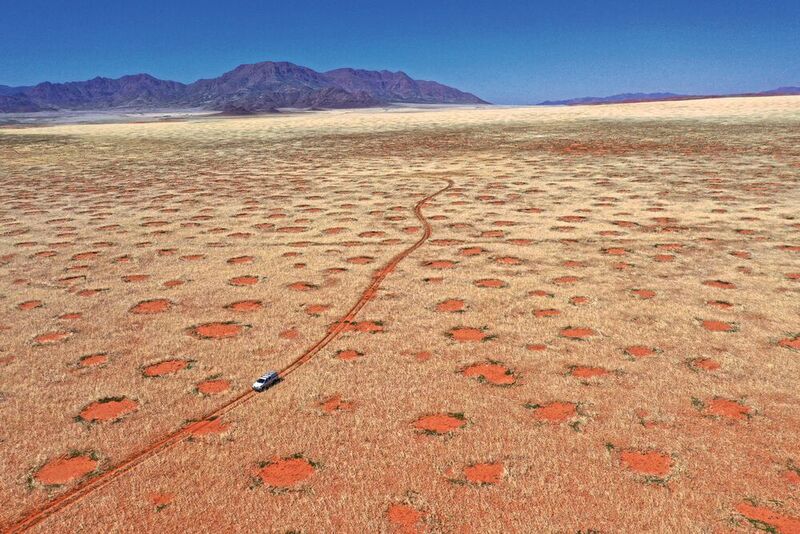 Drohnenaufnahme eines Autos im Namib-Rand-Naturreservat, eine der Feenkreisregionen in Namibia, wo die Forscher Gräser, Bodenfeuchte und Infiltration untersuchten (April 2022).