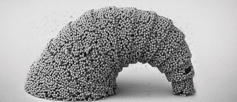 Rasterelektronenmikroskopische Aufnahme einer hängenden, croissantförmigen Mikrostruktur mit einer 3D-gekrümmten Oberfläche, die aus SiO2-Partikeln zusammengesetzt ist.(Bild:  MPI-IS)