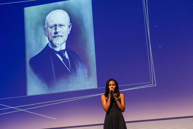 Eventmanagerin Ursula James, Vogel Business Media, besingt den Firmengründer Carl Gustav Vogel mit einem eigens geschriebenen Song. (Vogel Business Media / S. Bausewein)