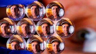 The visage of Stephen Morin, associate professor of chemistry, refracts through an array of lenses. Morin and his Nebraska colleagues have crafted much smaller lenses — some of them substantially narrower than a human hair — whose size and optical properties can be modified in seconds when subjected to certain stimuli. (Source: Craig Chandler/ University of Nebraska–Lincoln)