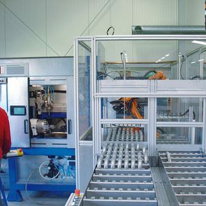 Die automatisierte doppelstrangige Teilezuführung der Laserschneidanlage (links): der Knickarmroboter (im Hintergrund) belädt die Maschinen immer mit dem passenden Werkstück.