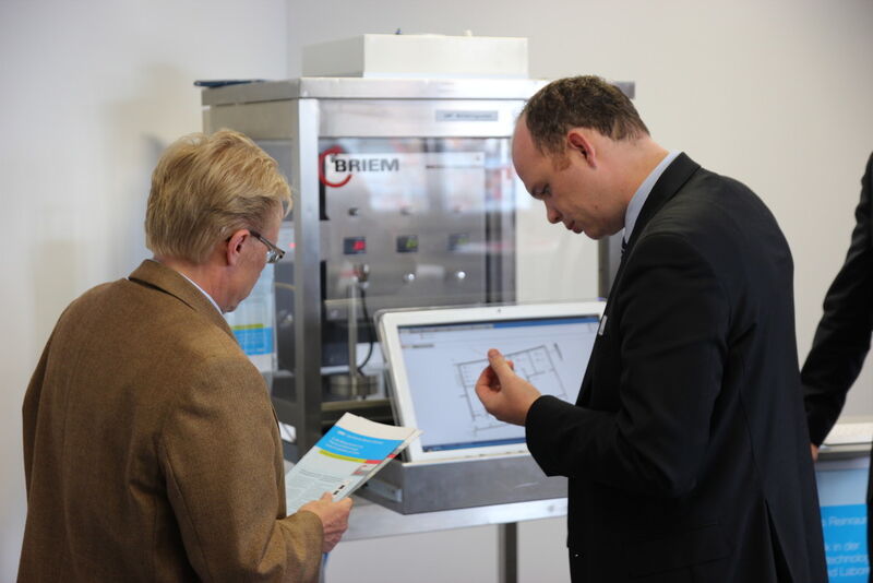 Matthias Alber (re.), Key Account Manager bei Briem Steuerungstechnik, zeigt einem Teilnehmer die ausgestellte Reinraumzelle. (Bild: Reinhardt)