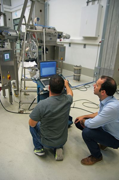 Ein Vertreter von Zeppelin (sitzend) und ein Softwareentwickler überprüfen die an der Anlage angebrachten Sensoren. (Bild: Oliver Thiel/Zeppelin)