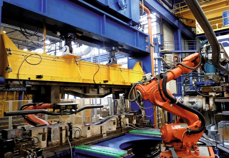 Die vorgeformten, an den Enden bereits abgeflachten Rohre werden von einem Roboter gegriffen und auf einer Palette vor der Gräbener-Roboclamp-Presse abgelegt. (Bild: Kuhn)