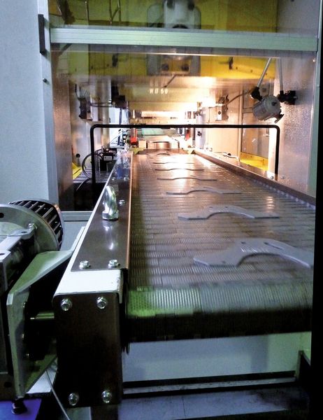 Die fertig gestanzten Teile werden auf einem Förderband aus der Presse transportiert und fallen dort in einen Sammelbehälter. (Bild: Kuhn)