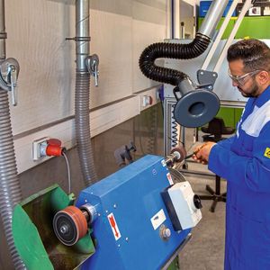 Die Fächerschleifmaschine ist via Schlauch und Rohrleitung an den Nassabscheider angeschlossen. Der Absaugarm kann bei größeren Staubmengen hinzugenommen werden.(Bild:  Esta)