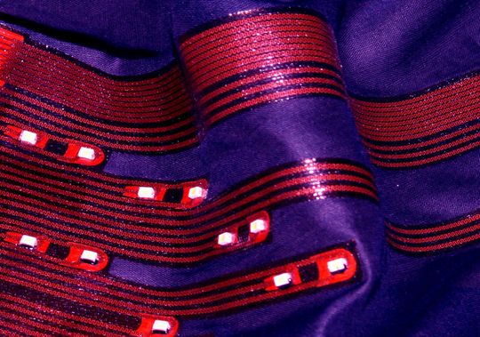 Smarte Textilien bieten für den Träger viele Vorteile: Auf dem Fachkongress im November tauscht sich die Branche aus. Das Bild zeigt Leuchtdioden, die nicht auf einer Platte oder einem Streifen sitzen, sondern auf einem weichen Stück Stoff. Entwickelt vom Fraunhofer IZM.(Bild:  Fraunhofer IZM)