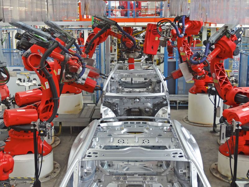 Beim Anbringen und Befestigen von Karosserieteilen bilden Roboter ein Spalier. Sie stehen in dichten Reihen nebeneinander und schweißen, nieten, falzen, bringen Bolzen und manches mehr – teilweise in parallel laufenden Prozessen. (Bild:)