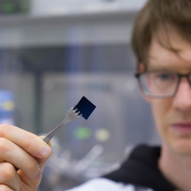 Stefan Schröder hält eine mit einer hauchdünnen Polymerbeschichtung versehene Siliziumprobe. Die Beschichtung ist mit bloßem Auge nicht sichtbar. (Bild: Christina Anders, Uni Kiel)