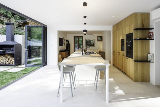 Zusammengefaltet und als unauffälliges Glaspaket auf der Terrasse geparkt, öffnet nach derSanierung eine Glasfaltwand den Innenraum zur Landschaft. (Bild:  Christoph Welkovits)