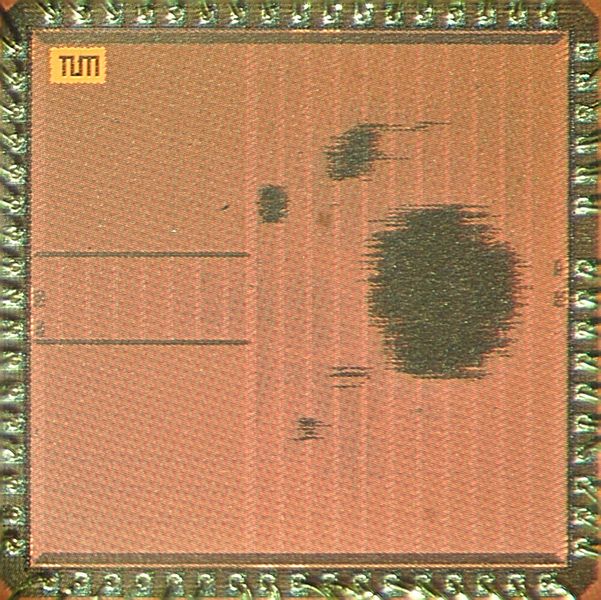 Chip-Fotografie des ASIC: Am Bildrand, umlaufend um den Chip, befinden sich die Anschlüsse für Ein- und Ausgabedaten sowie die Stromversorgung. Links sitzen die Speicherblöcke des Chips. Die Schattierung rechts ist der Bereich der höchsten Schaltungsdichte. Hier wurden die Post-Quanten-Beschleuniger auf dem Chip platziert. (Bild: Astrid Eckert / TUM)