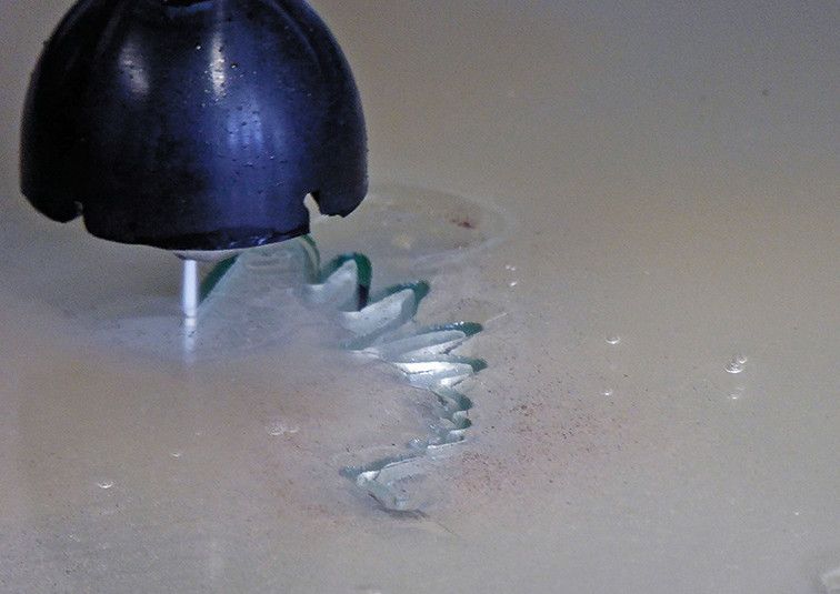 Die Wasserstrahlschneidmaschine hat Späth vor allem für den Zuschnitt und die Musterschnitte für seine Metallverarbeitung gekauft. In der Demonstration schneidet er Adler und Pferde aus Spiegelglas aus. (Bild: Kuhn)