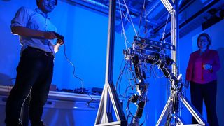 Doktorand Hongxi Zhu und Professorin Ulrike Thomas probieren gemeinsam den Laufroboter aus, in dem das nachgiebige Robotergelenk integriert werden kann. (Jacob Müller)